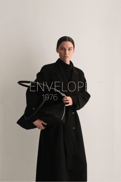 Envelope 1976 banner med modell i sort kåpe og veske mot lys bakgrunn